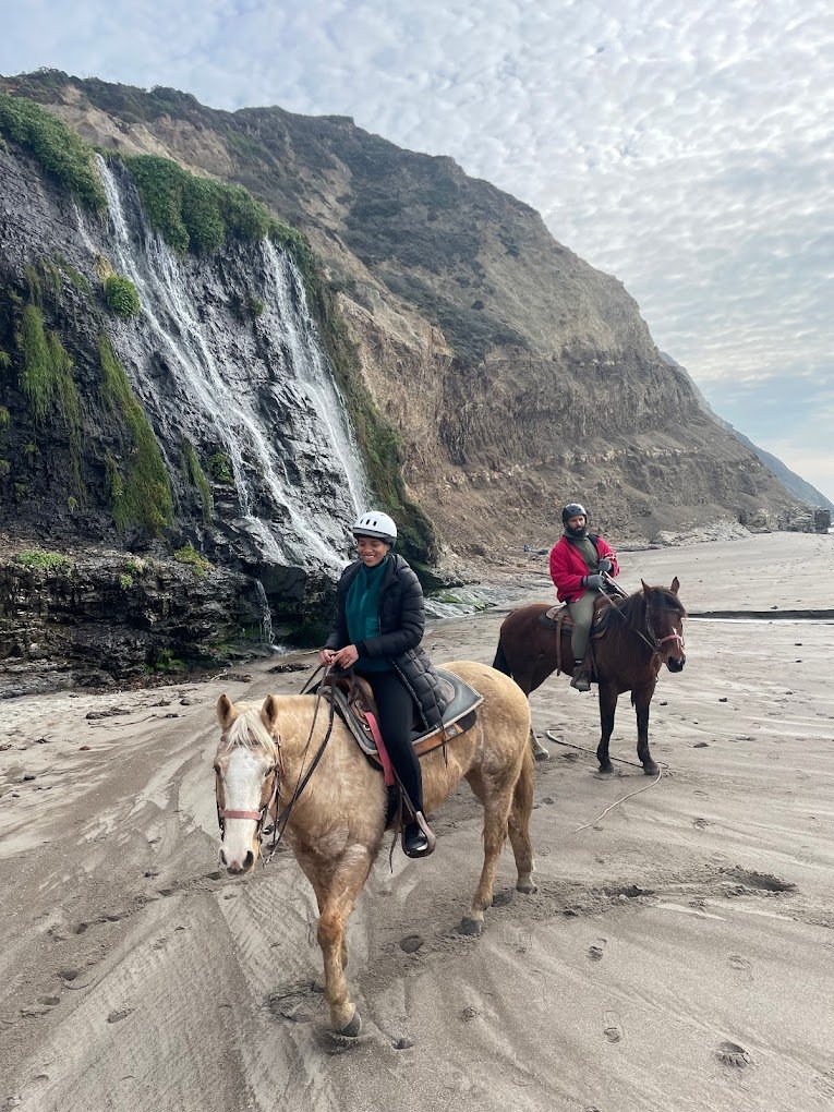 Couple On Horses Walking On Beach