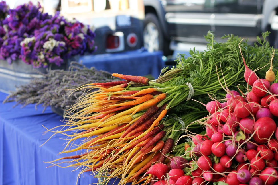 carrots, radishes, and flowers on a table at market